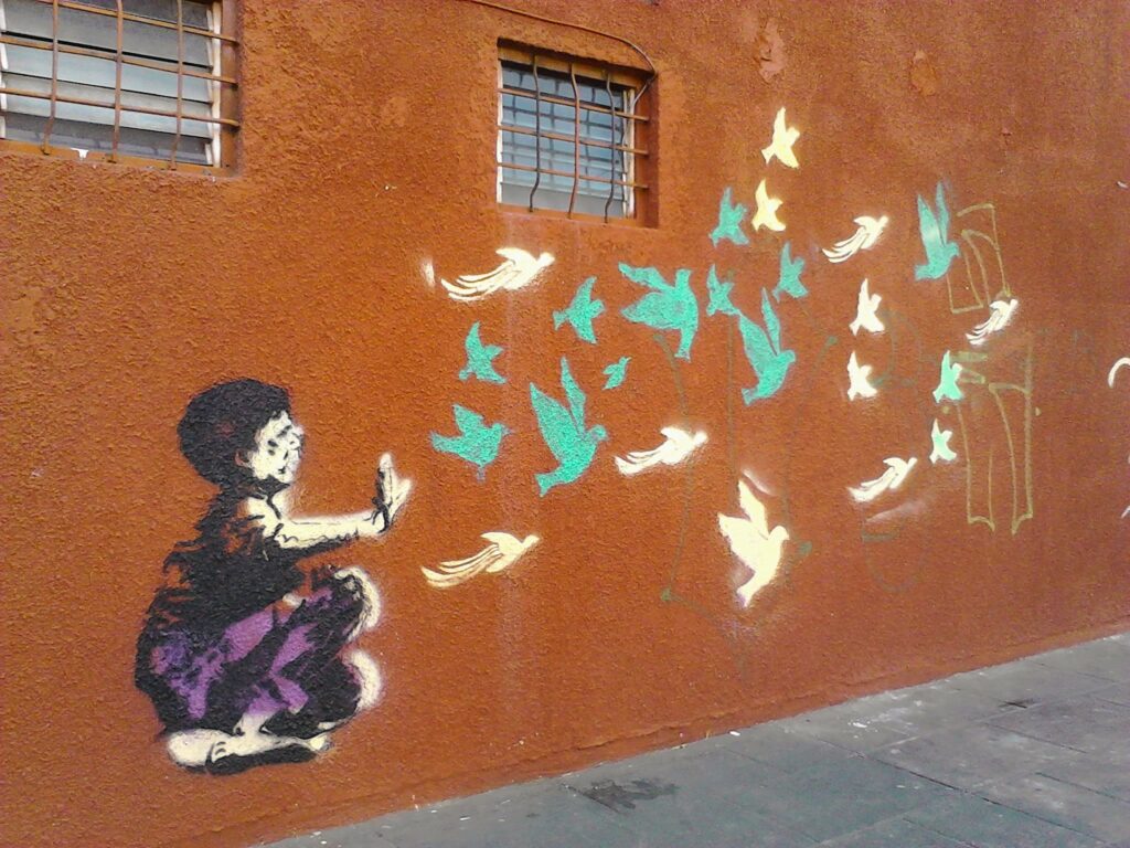 child sits on the ground and birds flying away from him